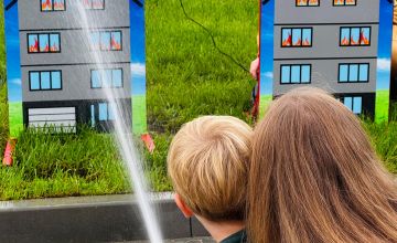 Dziecko z mamą celujące strumieniem wody do celu